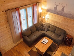 A cozy room with a sectional sofa, a wooden coffee table, and a wall-mounted light fixture.
