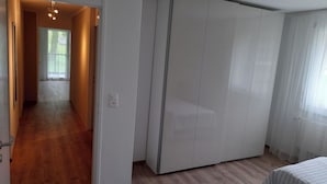 A bedroom with a wardrobe, a bed, and a bedside table.
