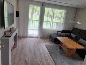 Una sala de estar moderna con un televisor de pantalla plana, un sofá, una mesa de centro de madera y una chimenea.