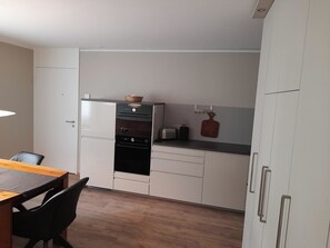 A compact kitchen with a refrigerator, oven, microwave, and a small countertop.