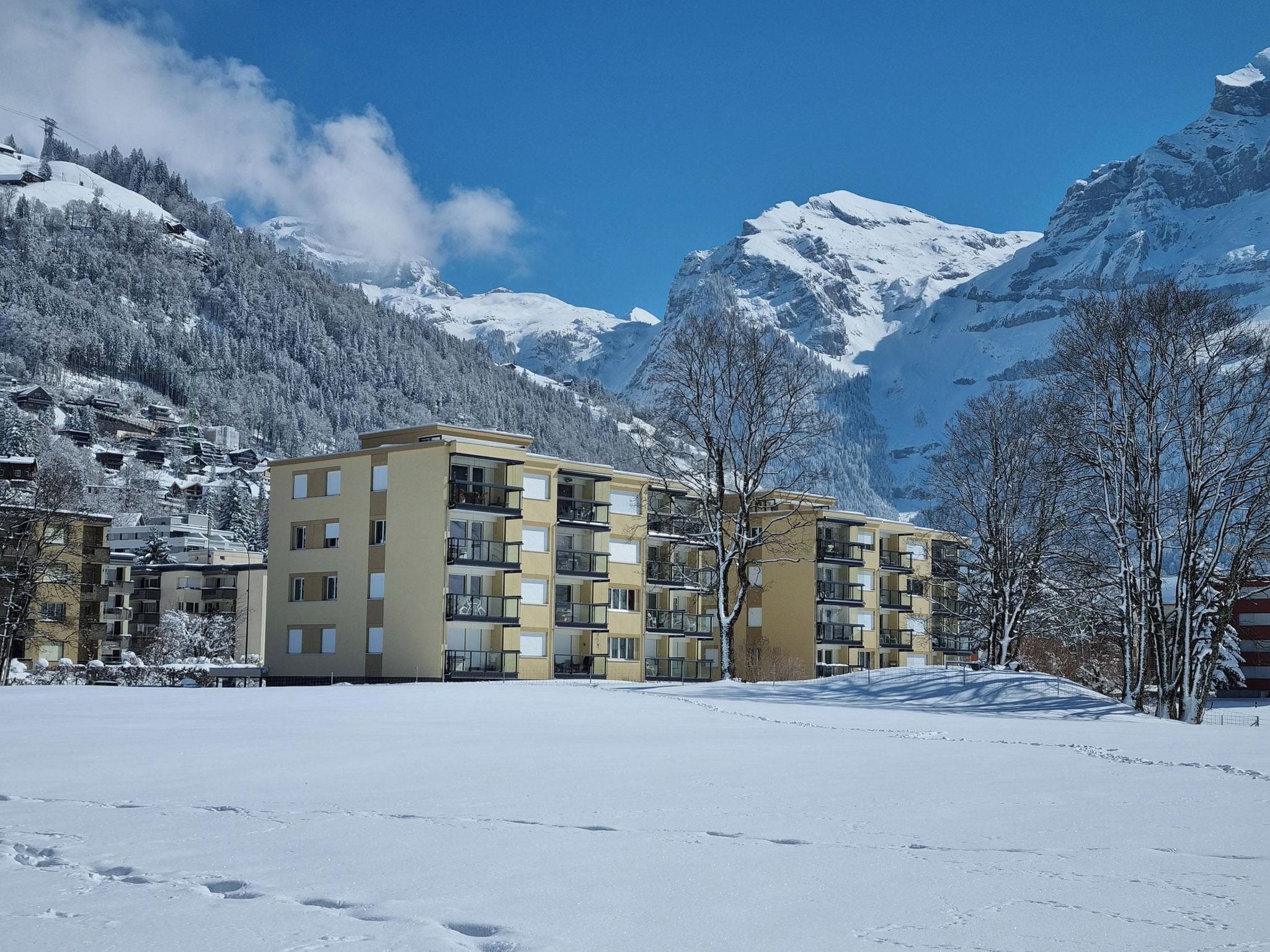 A multi-story hotel with a modern design, located in a snowy mountainous area with clear skies.