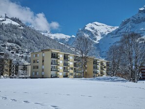 Un hotel de diverses plantes amb un disseny modern, situat en una zona muntanyosa nevada amb cel serè.