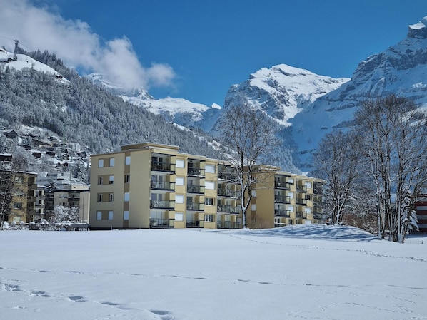 A multi-story hotel with a modern design, located in a snowy mountainous area with clear skies.