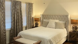 A bedroom with a bed, a ceiling fan, a nightstand, and a window with curtains.