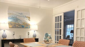 A dining area with a wooden table, brown leather chairs, and a chandelier.