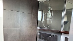 Ein modernes Badezimmer mit Duschkabine aus Glas, Waschbecken und Spiegel.