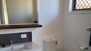 Ein modernes Badezimmer mit Waschbecken, Spiegel und Toilette in Weiß.