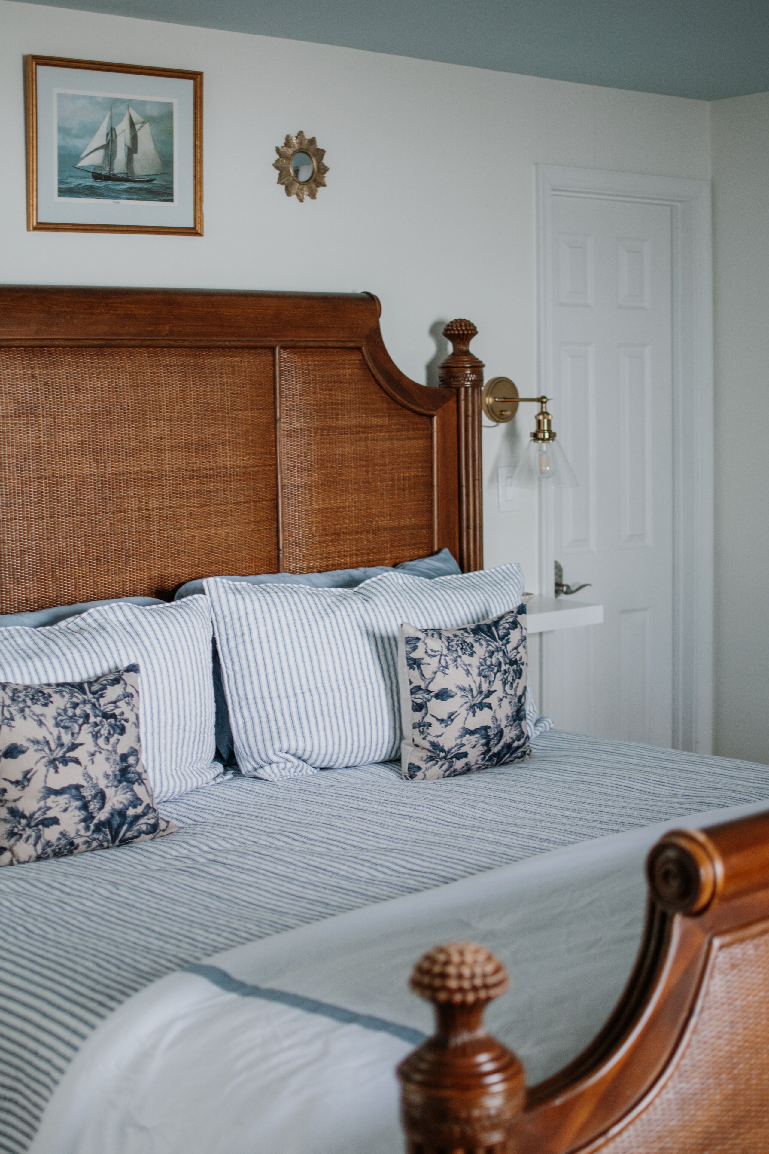 Un dormitorio con cabecera de madera, ropa de cama a rayas y una mesita de noche con lámpara.