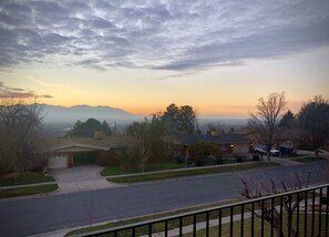 Une rue résidentielle bordée de maisons, un ciel dégagé et des montagnes à l’horizon.
