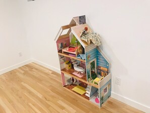Une maison de poupée avec plusieurs pièces, dont une cuisine, un coin repas et une chambre à coucher.