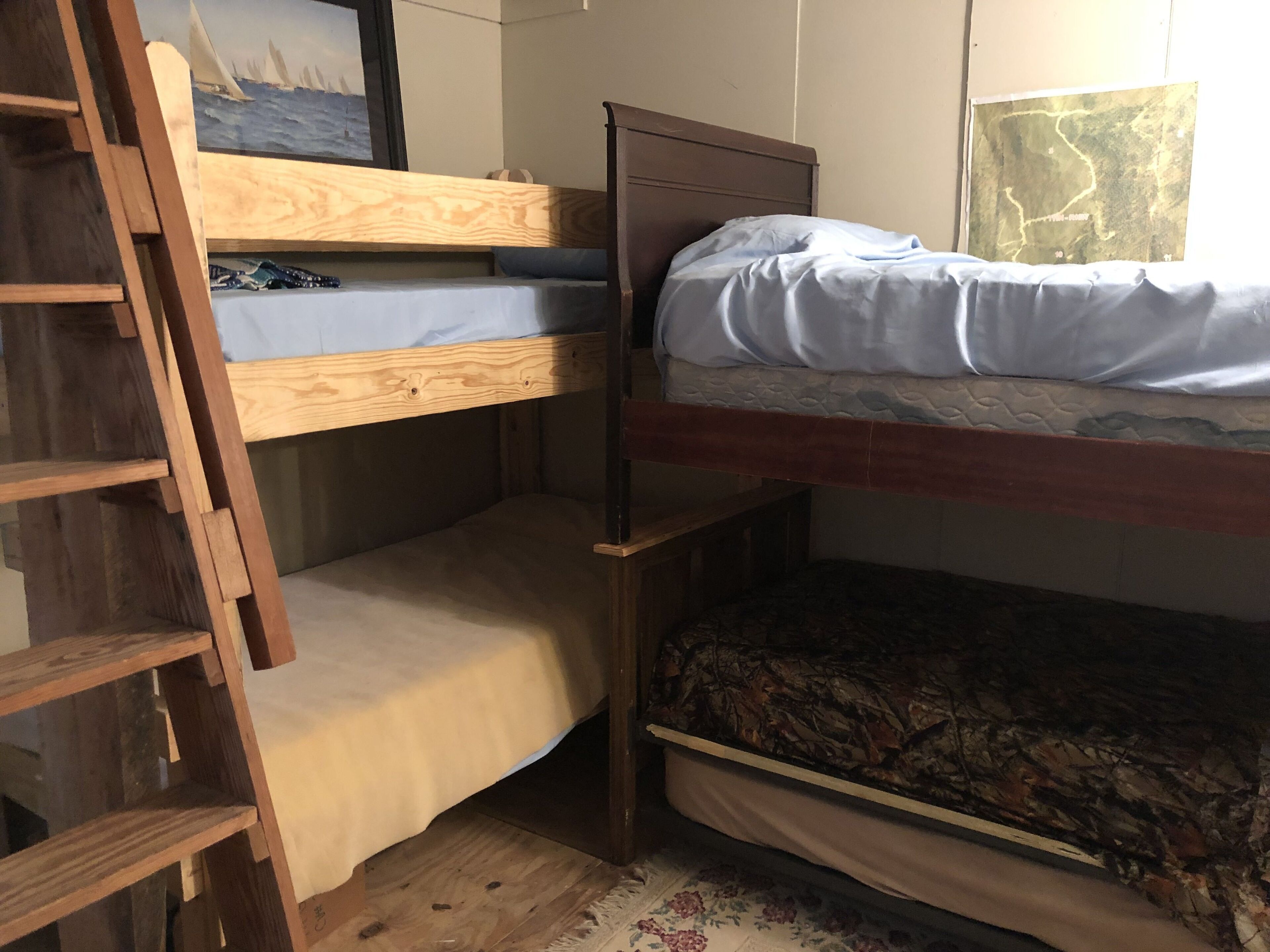 A bunk bed room with a wooden ladder, a map on the wall, and a floral rug.
