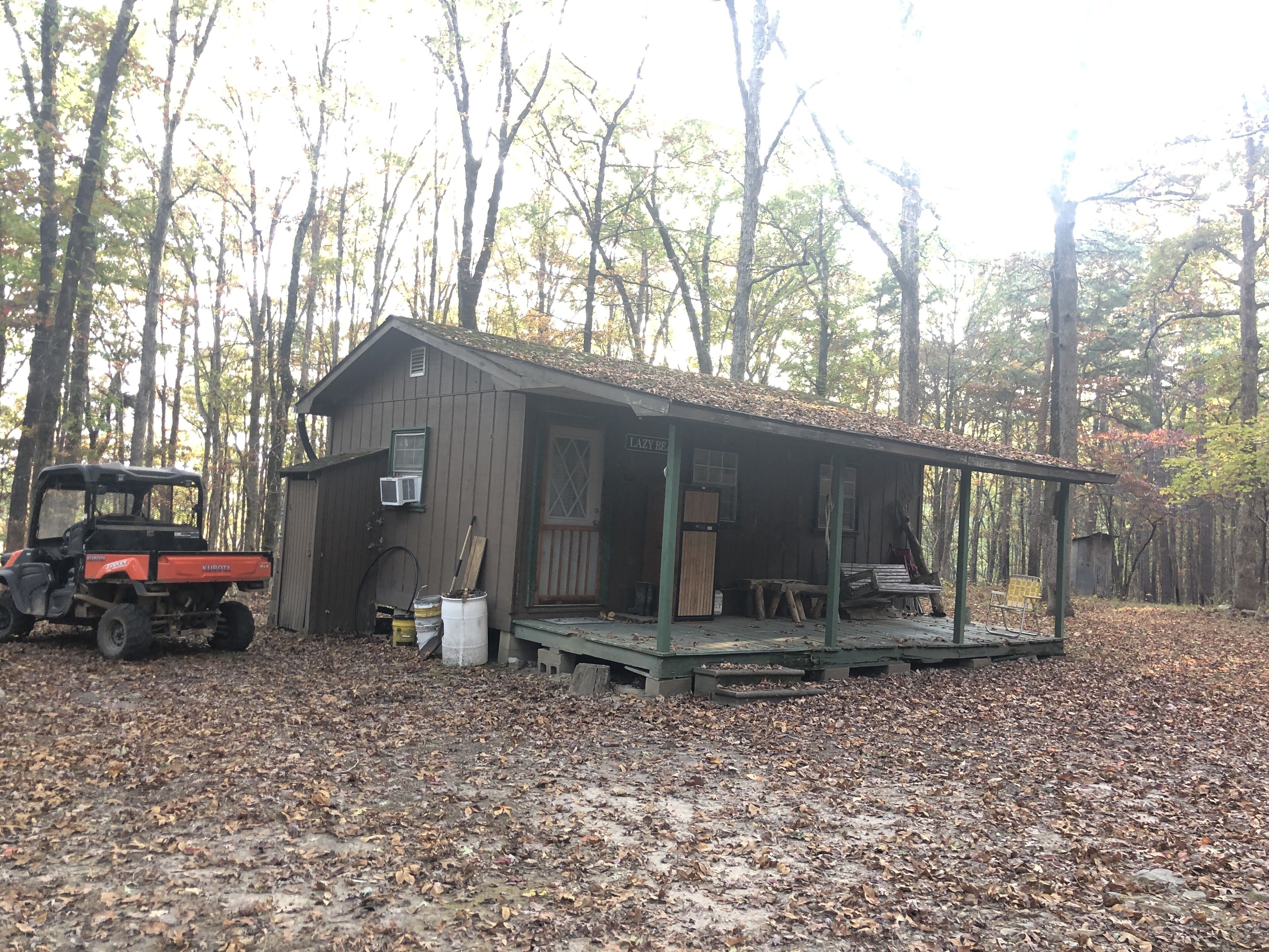A rustic cabin with a porch, surrounded by trees.