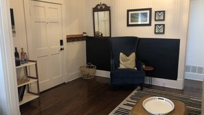 A room with a dark blue sofa, a white door, a mirror, and framed pictures on the wall. - J Birds' Bungalow (Memphis)