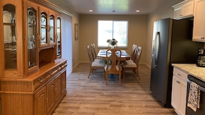 A kitchen with wooden cabinets, a dining table with chairs, a refrigerator, and a window with blinds. - Taylor II House, ocean view, close to everything (Crescent City)