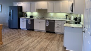 A modern kitchen with white cabinets, a stainless steel refrigerator, and a granite countertop. - Taylor II House, ocean view, close to everything (Crescent City)