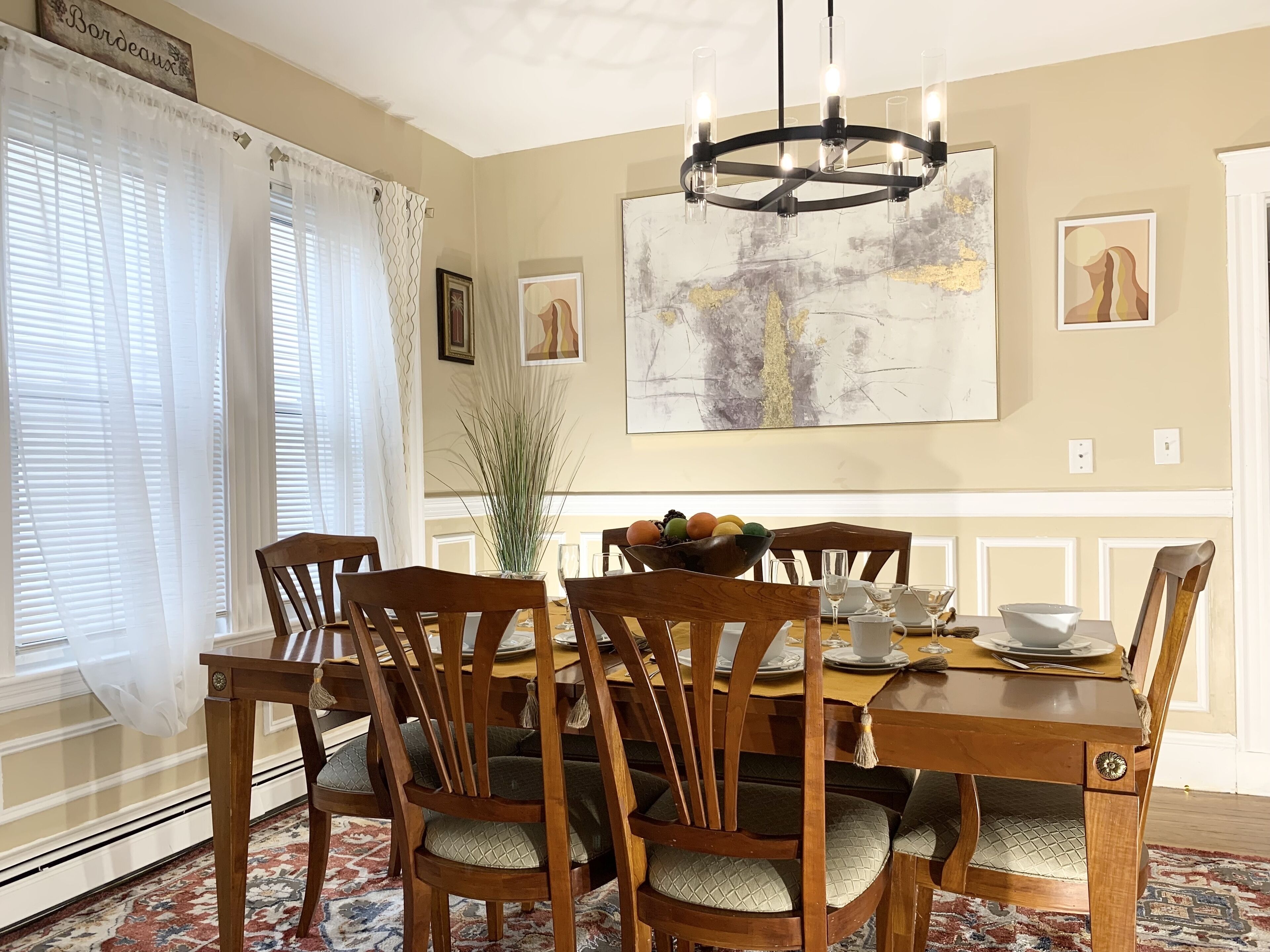 A dining room with a wooden table, chairs, and a chandelier.