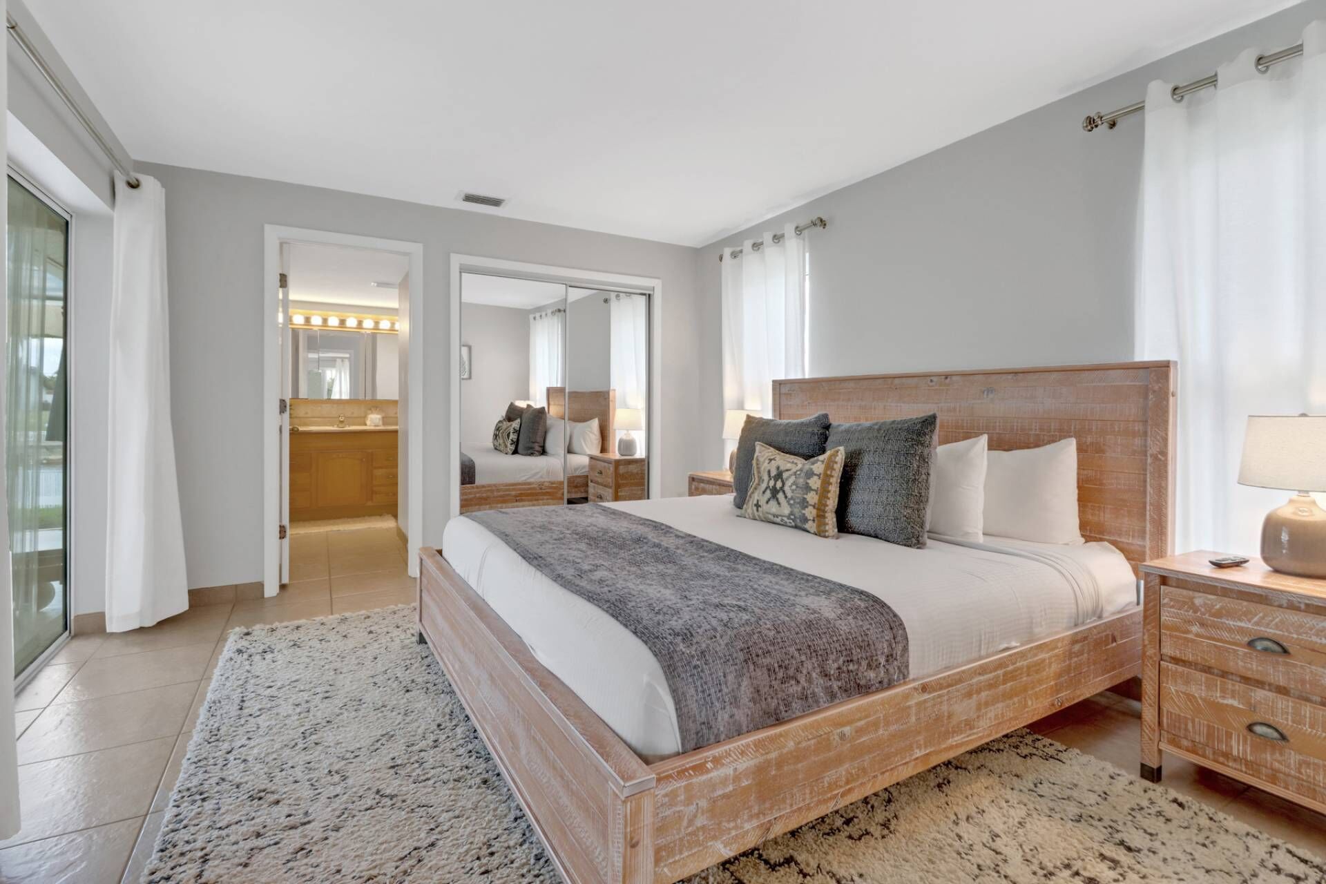 A bedroom with a large bed, a wooden headboard, a nightstand, and a mirror.