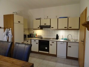 A compact kitchen with white cabinets, a stove, a dishwasher, and a sink.