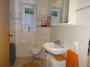 A bathroom with a toilet, sink, and window. - Nord-Ostsee-Nest: Apartment with sun terrace and wallbox - Nord-Ostsee-Nest (Tarp)