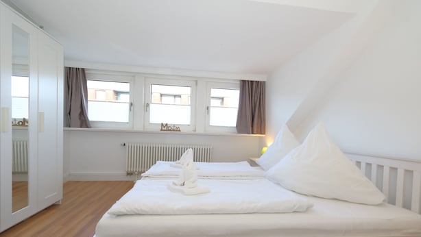 Et soveværelse med seng, et vindue, en radiator og en dør.