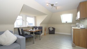 En moderne lejlighed med spiseplads, sofa, lille bord og køkken.