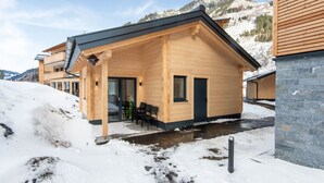 Une cabane en bois dotée d’un balcon, d’un porche abrité et d’un mur en pierre.