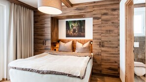 Une chambre à coucher moderne avec une tête de lit en bois, un grand lit et un luminaire suspendu au plafond.