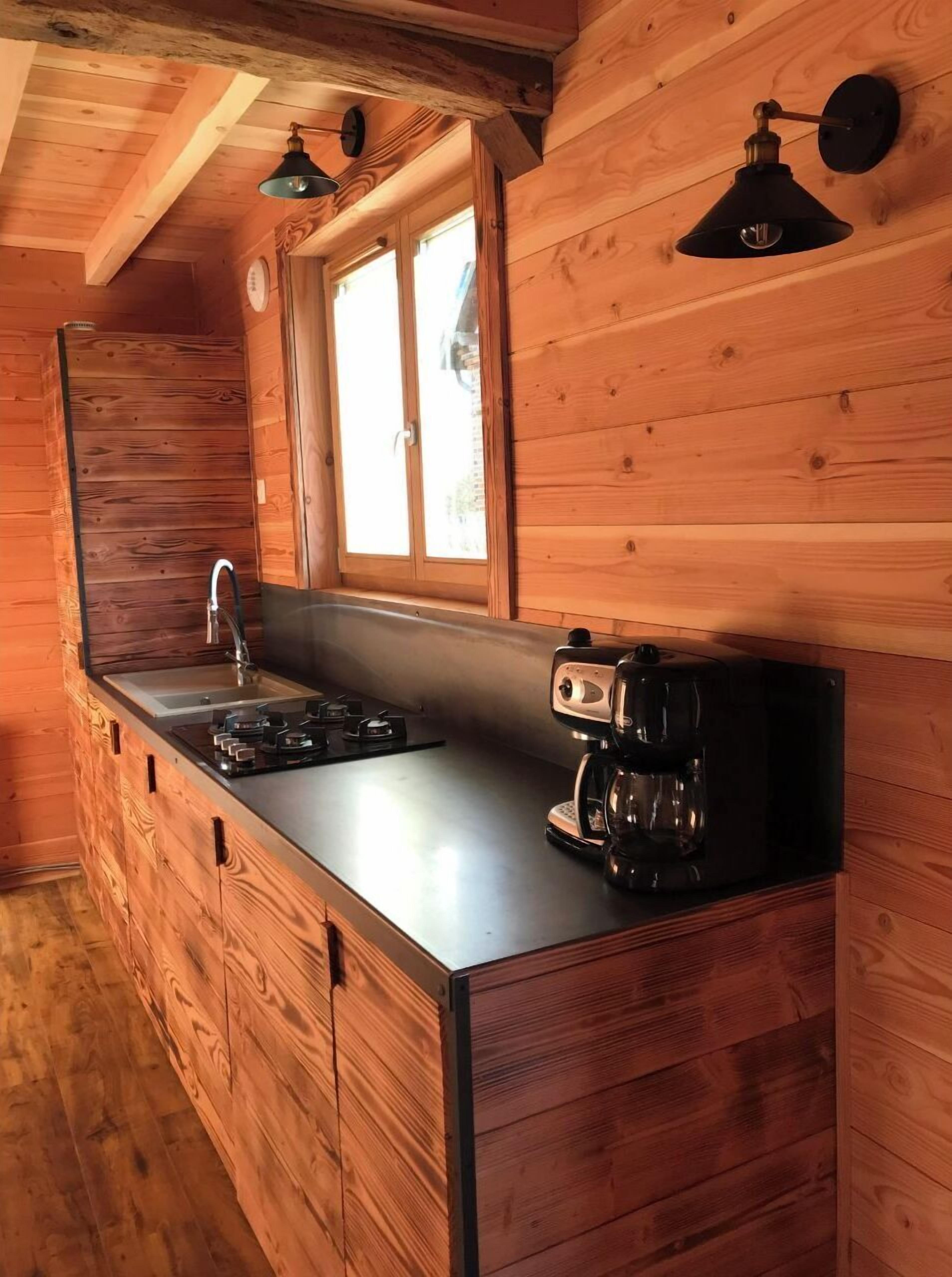 A wooden cabin kitchen with a built-in sink, a stove, and a coffee maker.