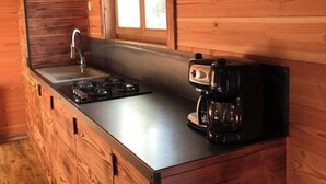 Een houten keukentje met een inbouwspoelbak, een fornuis en een koffiezetapparaat.