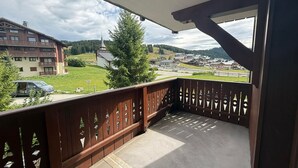 A balcony with a view of a town, a church, and a car parked nearby.