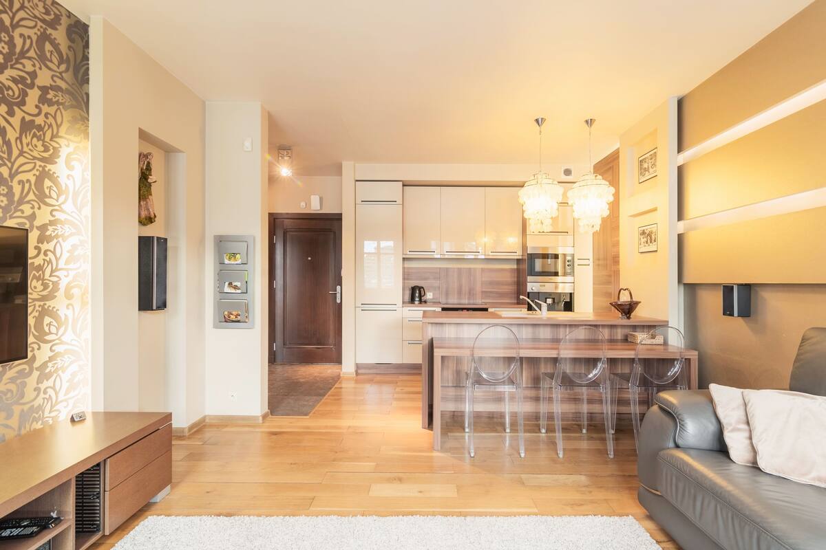 A modern living room with a grey sofa, a TV, and a wooden entertainment unit.