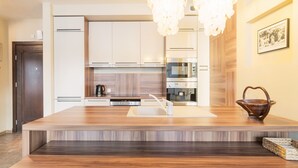 A modern kitchen with a wooden island, stainless steel appliances, and pendant lighting. - Grand Apartments - Willa Morska (Sopot)