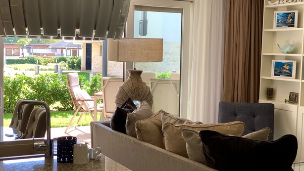 A living room with a sofa, a lamp, a coffee table, and a view of the outdoors. - Lakeside condo with beach access (Csopak)