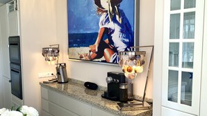 A modern kitchen with a granite countertop, a coffee machine, and a painting of a woman on the wall. - Lakeside condo with beach access (Csopak)