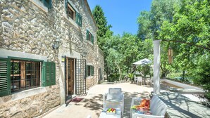 A stone building with a patio area featuring wicker furniture and a table with fruit. - VILLA PLOMER - 2 MIN WALK TO THE OLD TOWN (Pollensa)