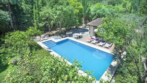 A rectangular swimming pool with a tiled deck, surrounded by lush greenery and trees. - VILLA PLOMER - 2 MIN WALK TO THE OLD TOWN (Pollensa)