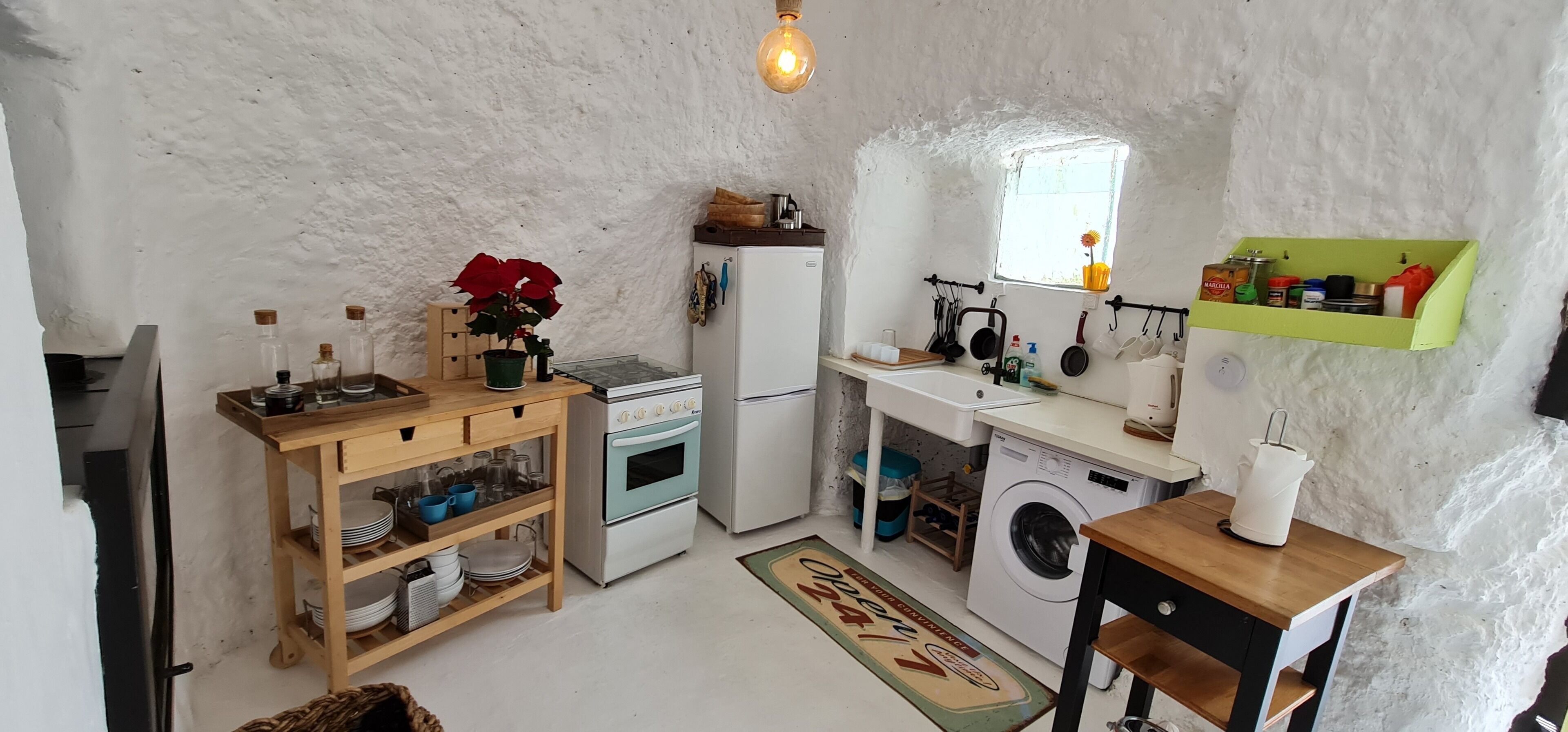 Cocina compacta con estufa, horno, lavadora y una ventana pequeña.