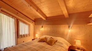Une chambre à coucher aux murs lambrissés, avec un lit, deux lampes de chevet et une fenêtre avec des rideaux.