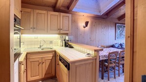 Une cuisine compacte avec des meubles en bois, un lave-vaisselle encastré et un petit îlot central doté d’un évier.