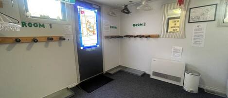 A hallway with two rooms labeled Room 1 and Room 3, a door with a sign, a radiator, and a small trash can.