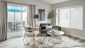 Ein modernes Wohnzimmer mit Glastisch, einer Couch und einem Essbereich mit Stühlen.