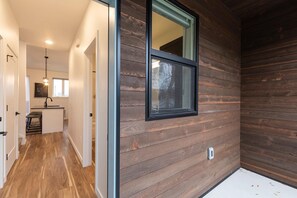 Cozy living space with a kitchen area, wooden paneling, and a window offering a view of the outdoors.