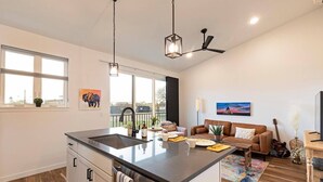 Une cuisine moderne dotée d’un îlot central, de grandes fenêtres et d’un coin repas avec un canapé et une guitare.