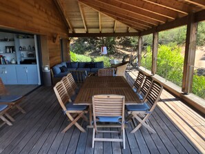 Relax on the deck with a central table and six chairs, surrounded by a lush landscape.