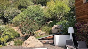 A swimming pool with lounge chairs and a lamp, surrounded by lush greenery and rocky terrain. - Magnificent sea view villa 500m from the beach and 10min from Porto-Vecchio (Porto-Vecchio)