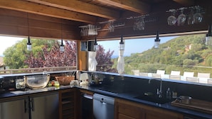 A kitchen with wooden cabinets, a black countertop, and hanging wine glasses. - Magnificent sea view villa 500m from the beach and 10min from Porto-Vecchio (Porto-Vecchio)