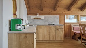 Une cuisine avec des meubles de rangement en bois, une machine à café verte et une fenêtre avec des rideaux.