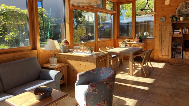 Un intérieur chaleureux en bois, avec un canapé, une table à manger, des chaises et une bibliothèque.