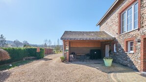A stone building with a gravel driveway and a covered outdoor seating area.