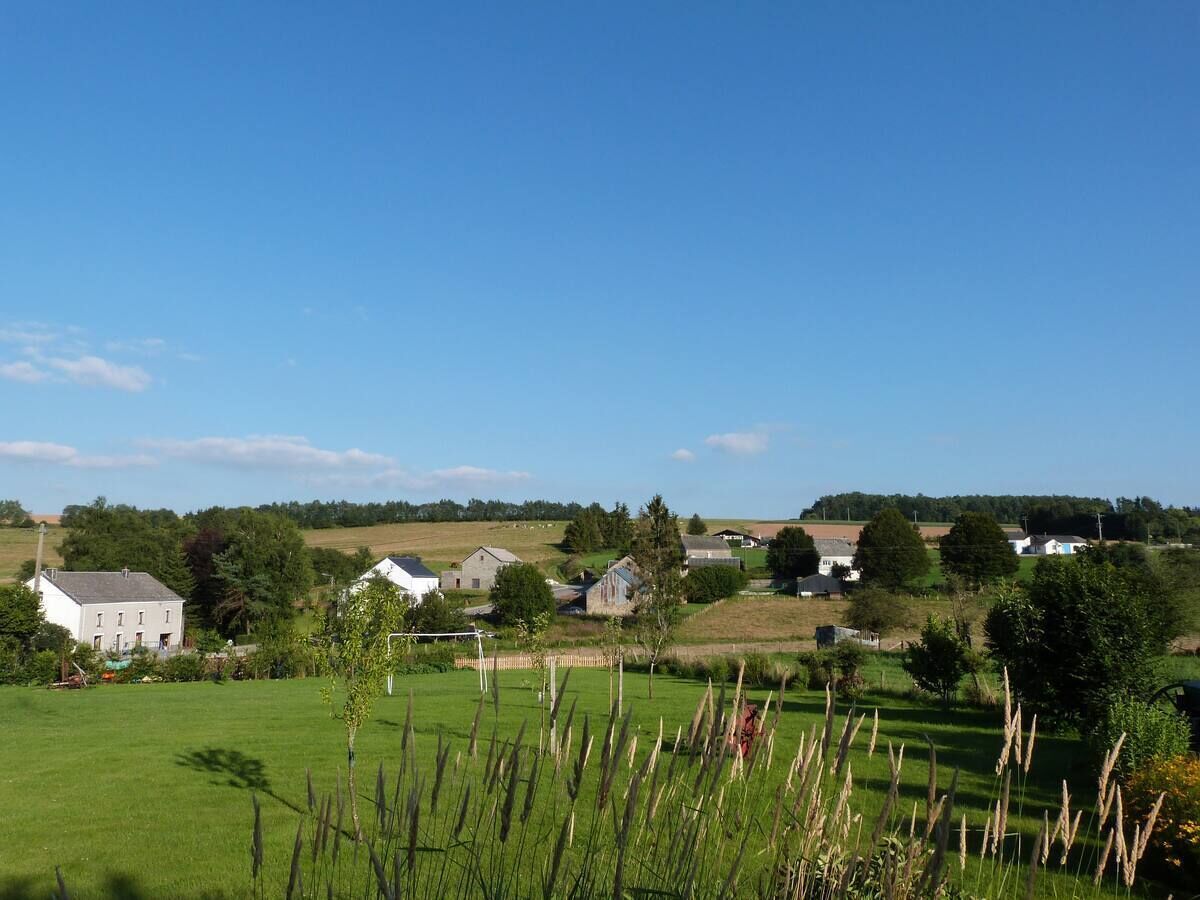 A rural landscape with houses, open fields, and a clear sky.